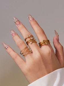 Macro detail of gold-plated rings set featuring cubic zirconia and twisted knot designs