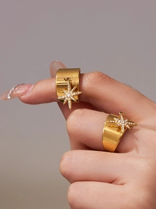 Macro shot of 18k gold plated wide rings featuring dangling star charms with zircon stones
