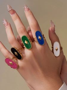 Détail de cinq bagues ovales en émail coloré rose noir vert bleu et blanc sur les doigts