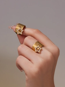 Macro detail of 18k gold plated wide star ring with zircon stones on female fingers