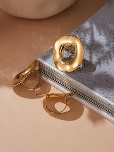 Detailed view of three irregular wavy 18k gold plated stainless steel rings on books