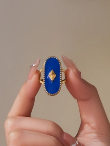 Détail d'une bague dorée bohème avec émail bleu roi et bordure à perles de style vintage