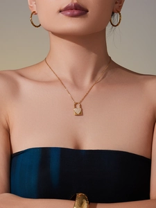 Dettaglio della collana con pendente a lucchetto a cuore placcato oro 18k indossata da modella