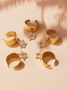 Detailed view of five gold-plated rings with zircon-studded hollow star charms in sunlight