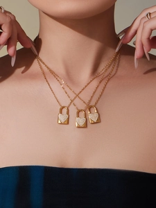 Dettaglio di collane a tre strati placcate in oro 18k con ciondoli a lucchetto a cuore in zirconi