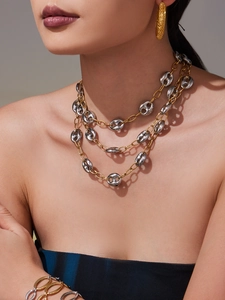 Close-up of layered two-tone chunky chain necklace and matching earrings on a model