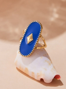 Vue détaillée d'une bague bohème en émail bleu avec détails dorés sur un coquillage