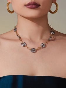 Detail of two-tone gold and silver coffee bean link necklace and textured hoop earrings