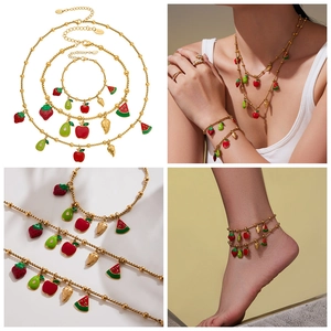 Detail of fruit charms jewelry set with strawberry and apple pendants on gold steel