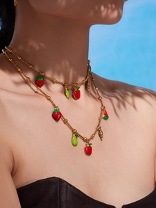 Detailed view of a gold beaded necklace with colorful fruit charms on a model