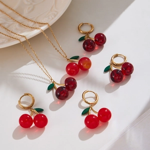 Elegant red resin cherry pendant necklace and earring set with golden leaf details