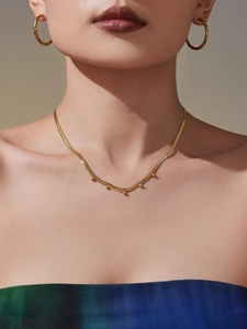 Poliertes Gold-Schlangenkette mit Perlen und gedrehte Creolen-Ohrringe am Modell