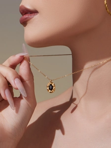 Close-up of gold oval black zircon pendant necklace worn by a fashion model