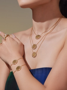 Détail de colliers arbre de vie superposés et bague léopard avec zircons dorés