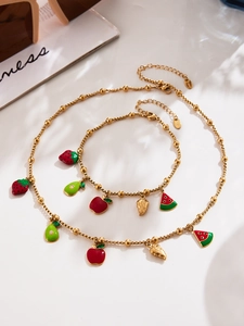 Detail of gold stainless steel fruit enamel charms on necklace and bracelet set