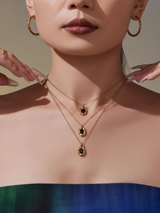 Detail of triple-layered gold necklaces with oval black gemstone pendants on model