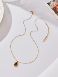Macro detail of oval black zircon pendant with golden textured edges and fine chain