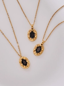 Macro shot of oval gold pendant necklaces with black zircon stone and vintage sunburst texture