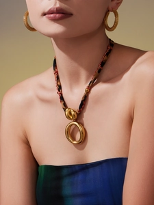 Close-up of golden heart pendant on leopard print scarf necklace with matching hoop earrings
