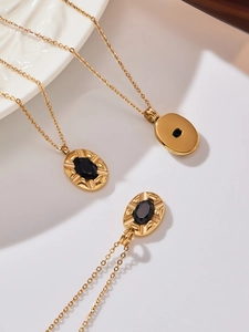 Close-up of golden oval pendant with black zircon stone and radial metal texture