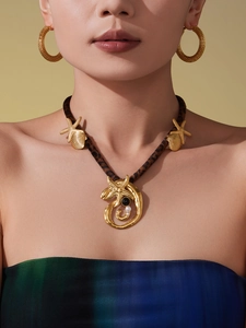 Close-up of leopard print necklace with gold starfish pendant and woven hoop earrings