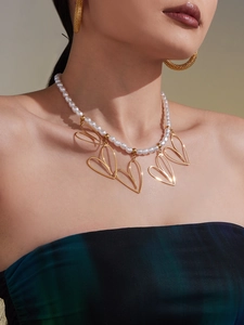Dettaglio della collana di perle con ciondoli a cuore dorati su una modella