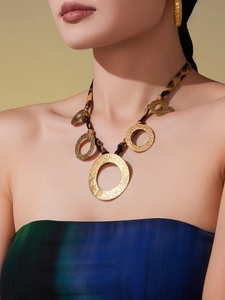 Detail of leopard print fabric necklace with gold hammered rings on a female model
