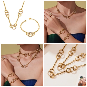 Détail des anneaux dorés entrelacés sertis de zircons sur parure de bijoux à grosse chaîne
