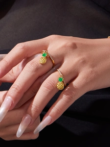 Détail de deux bagues ananas dorées avec émail vert et cristaux jaunes brillants