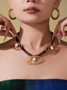 Macro detail of leopard print lanyard necklace with gold oval rings and white pearls