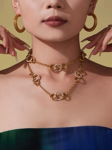 Gros plan du collier à anneaux entrelacés et des boucles d'oreilles créoles dorées sur modèle