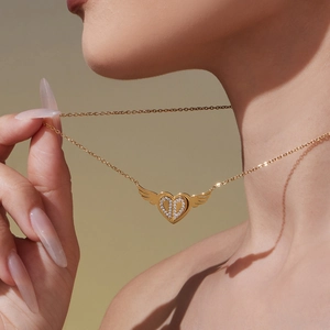 Goldene Herzkette mit Engelsflügeln und Kristalleinlage am Hals eines Modells