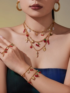 Detailed shot of gold jewelry set with enamel charms, layered necklace and rings