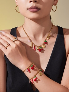 Détails des breloques cerise et fleurs plaquées or 18K portées par un mannequin