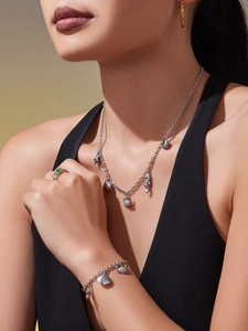Détail d'un ensemble collier et bracelet argenté thème océan avec breloques sur modèle