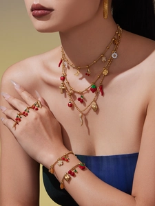 Detail of colorful enamel cherry and strawberry charms on a gold multi-layer necklace set