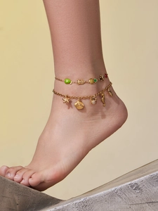 Vue détaillée des bracelets de cheville dorés avec pendentifs marins et fruits colorés