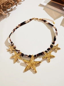 Detail of leopard print silk scarf necklace featuring golden starfish pendants and clasp