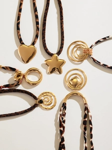 Detail of leopard print silk scarf necklace with polished gold heart and geometric charms