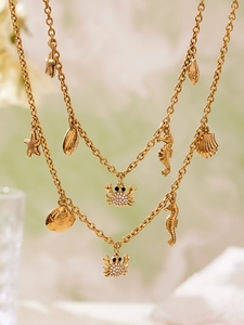 Gros plan de colliers dorés thème océan avec pendentifs étoile de mer, hippocampe et crabe