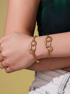 Détail d'un bracelet doré à anneaux imbriqués avec oxydes de zirconium au poignet
