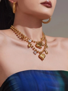Gros plan du collier plaqué or avec breloques cœur et ours et boucles d'oreilles créoles