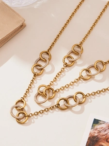 Vue détaillée de bagues dorées entrelacées avec zircone cubique sur collier élégant