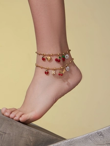 Golden beaded anklets featuring colorful enamel pendants of ladybugs, cherries, and daisies