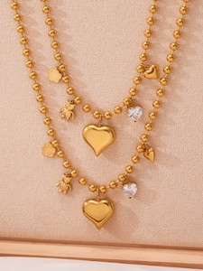 Détail macro d'un collier à billes plaqué or 18 carats avec breloques cœur et ours