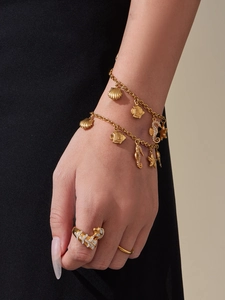 Dettaglio del bracciale dorato con ciondoli a stella marina, conchiglia e zirconi blu