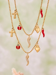 Detail of gold beaded necklace with red enamel ladybug, heart, and zircon horn charms