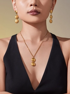 Close-up of a model wearing the golden textured ring necklace and earring jewelry set