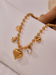 Détail du collier de perles en or 18 carats avec pendentifs cœur, ours et zircon