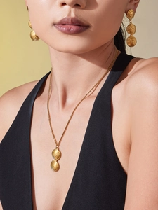 Detail of gold spiral textured necklace and earrings set on a model's neck and ears